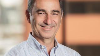 Yonatan is pictured smiling and facing forward. He is wearing a button down shirt with a subtle light grey and light blue strip pattern.